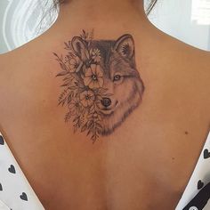 a woman with a tattoo on her back that has a wolf and flowers on it