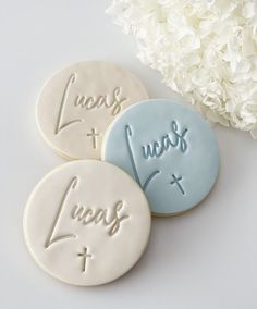 three cookies with words on them sitting next to a white flower