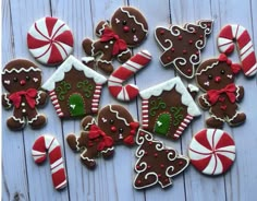 decorated gingerbread cookies arranged on a white wooden table with candy canes and candies