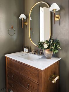 a bathroom with a sink, mirror and lights on the wall next to a wooden cabinet