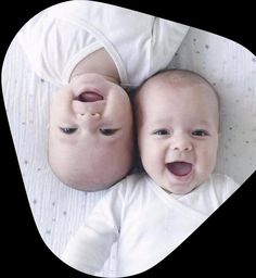 two babies laying next to each other on top of a bed