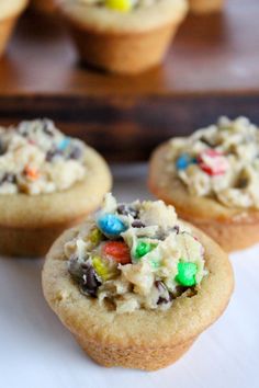 three cookies with m & m on top are sitting on a white plate and one is half eaten