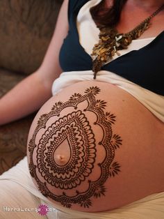 a pregnant woman with henna tattoos on her belly