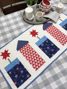 a quilted table runner with red, white and blue stars on the border is sitting on a dining room table