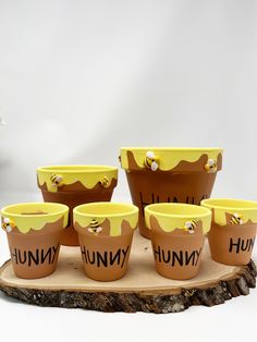 there are many cups with the word hummus painted on them sitting on a piece of wood