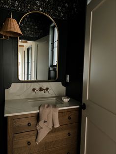 a bathroom sink with a mirror above it and a towel hanging on the counter top