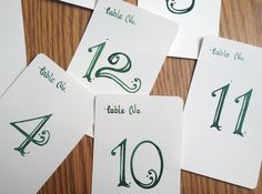 four cards with numbers and symbols on them sitting on a table top, all in green ink