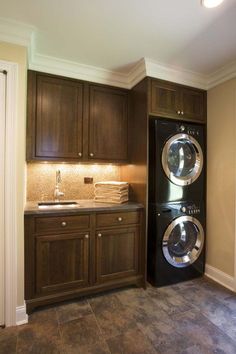 a washer and dryer are in the corner of this laundry room with dark wood cabinets