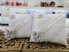 two white pillows with flowers and pearls on them