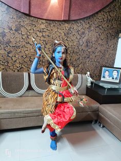 a woman with blue paint on her face and arms is dancing in front of a couch