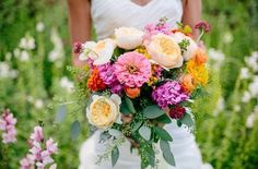 a woman holding a bouquet of flowers in her hands and wearing a white wedding dress