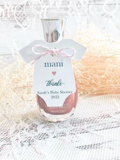 a bottle of baby shower gel sitting on top of a lace covered tablecloth with a pink bow