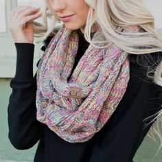 a blonde woman wearing a multicolored knitted scarf with a button on it