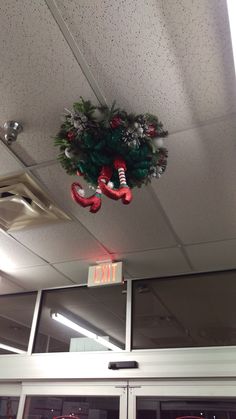 a christmas wreath hanging from the ceiling above an exit sign