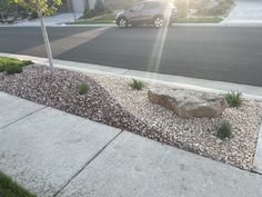 a car is parked on the side of the road next to a rock and grass bed