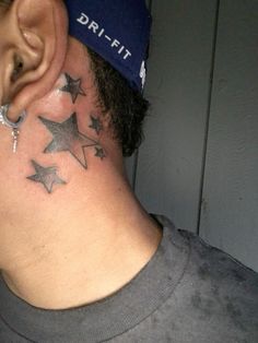 a man with stars on his neck is wearing a hat and ear piercings,