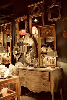 a room filled with lots of antique furniture and mirrors on the wall next to each other