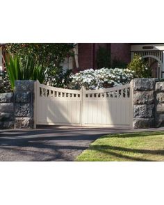 a stone wall and gate in front of a house with flowers growing on the fence