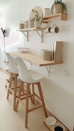 a kitchen with white chairs and wooden shelves on the wall next to a counter top