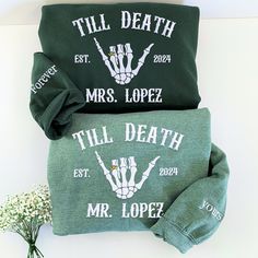 two green bags sitting next to each other on top of a white table with flowers