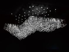 an artistic chandelier hanging from the ceiling in a dark room with white lights