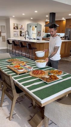 a man standing in front of a table filled with plates of food and bowls on top of it