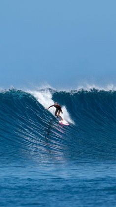 a man riding a wave on top of a surfboard in the middle of the ocean