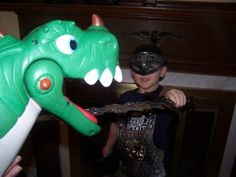 a young boy is playing with an inflatable dinosaur toy while another child looks on