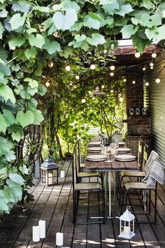 an outdoor dining area with lots of greenery on the roof and tables set for four