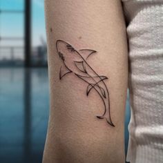 a woman's arm with a small tattoo of a shark on the left side