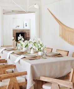 a dining room table set with place settings and flowers on the plates, in front of a fireplace