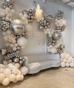 a couch sitting under a bunch of balloons next to a wall with the word bridal on it