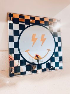 a mirror with a smiley face and two lightning boltes on it's side