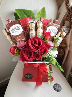 a bouquet of red roses and chocolates in a gift box on a table next to a window