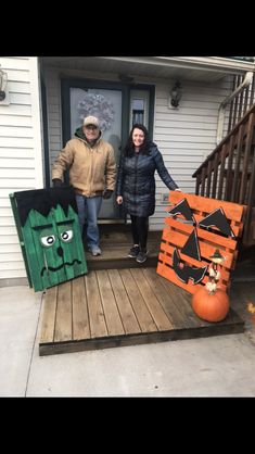 two people are standing on the front porch with their hand painted pumpkins and decorations