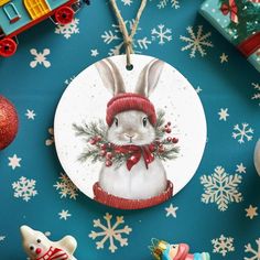 a christmas ornament with a rabbit wearing a red hat and scarf on it