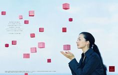 a woman standing in front of red cubes floating from the sky