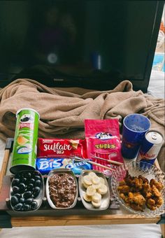 snacks and drinks on a tray in front of a tv