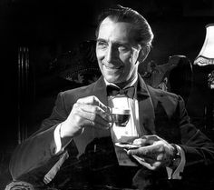 a black and white photo of a man in a tuxedo holding a glass of wine