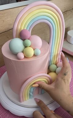 a person is decorating a cake with pastel colors