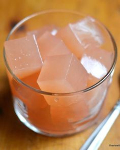 some ice cubes in a glass on a wooden table with a spoon and spoon