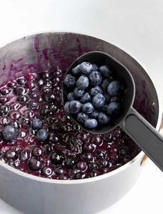 blueberries are being cooked in a saucepan with a ladle full of them