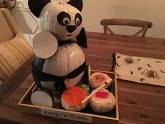 an inflatable panda sitting on top of a wooden table next to sushi