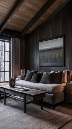 a living room with wood paneling and couches in front of a large window