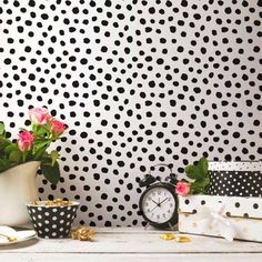 black and white polka dot wallpaper with pink flowers in vases next to an alarm clock