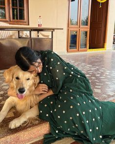 a woman in a green dress petting a brown dog on the steps at a building