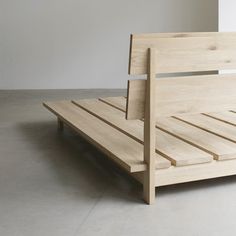 a wooden bed frame with slats on the bottom and foot board, in an empty room