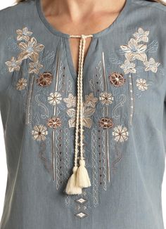 This beautiful baby blue short sleeve, light weight top has beautiful embroidered flowers in tan, brown, and cream and a cute tassel tie at the v-neck. 100% Cotton Casual Blue Tops With Tassel Ties, Summer Brown Blouse With Floral Embroidery, Light Blue Floral Embroidered V-neck Top, Blue V-neck Tops With Tassels, Blue V-neck Top With Tassels, Blue Spring Tops With Tassel Ties, Light Blue Embroidered V-neck Top, Blue Spring Top With Tassel Ties, Spring Blouse With Tassel Ties And Short Sleeves