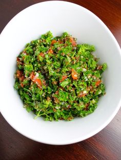 a white bowl filled with green vegetables on top of a wooden table