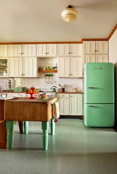 a green refrigerator freezer sitting inside of a kitchen